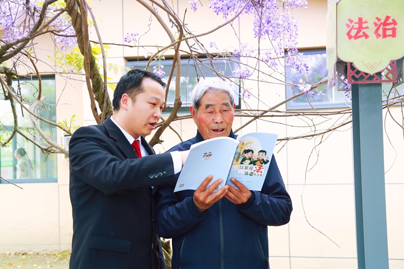 通州法院干警在紫藤花下与村民共读法治书籍.jpg